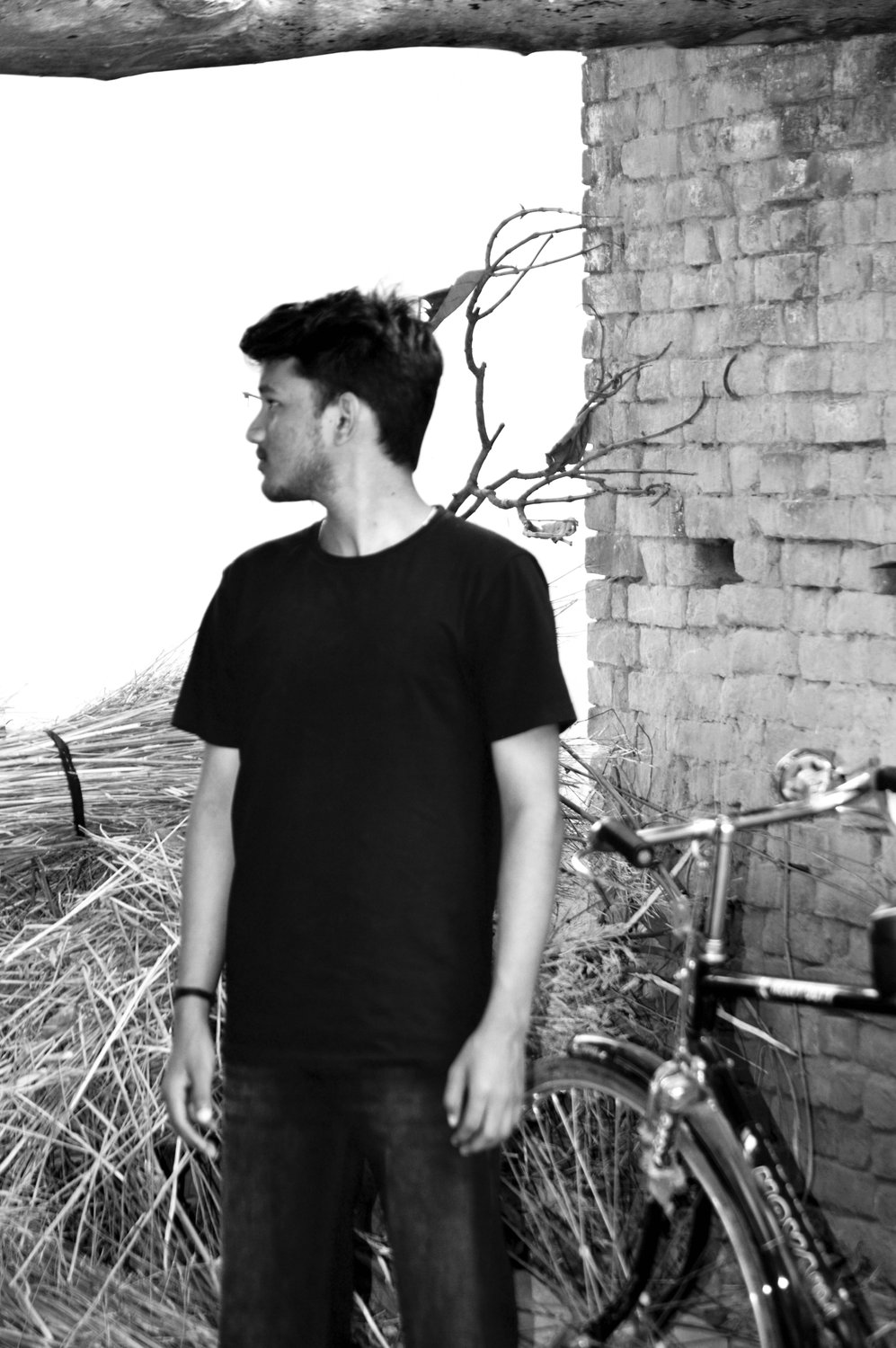 Before the ride — monochrome portrait beside a brick wall and bicycle